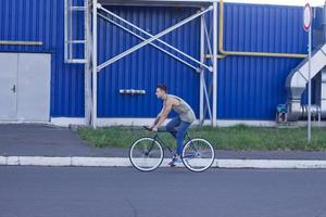 jeune homme marche avec vélo fixie, arrière-plan urbain, photo de hipster avec vélo aux couleurs bleues