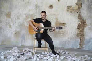 jeune homme avec guitare dans une pièce vide, musicien et auteur-compositeur seul dans le studio photo