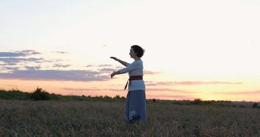 femme pratiquant le qigong dans les champs d'été avec un beau coucher de soleil sur fond photo