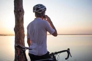 homme en casque debout et parlant téléphone avec beau lac sur backgraund photo