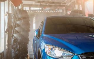 lavage de voiture suv bleu par machine à laver automatique. soins automobiles. nettoyage de voiture avec un jet d'eau à haute pression après nettoyage par brosse automatique. nettoyage de voiture avant le service de cirage. entreprise de service de lavage de voiture. photo