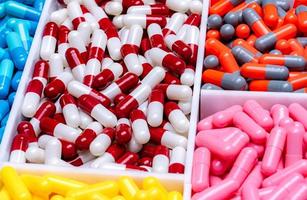 capsules de pilules dans un plateau en plastique. industrie pharmaceutique. production de drogue. notion de pharmacie. capsules de vitamines et de suppléments. capsules rouges, blanches, orange, grises, roses, jaunes et bleues.