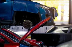 atelier de réparation automobile. la voiture rouge a ouvert le capot sur fond flou de la voiture suv bleue soulevée dans le garage pour le service de réparation et d'entretien. vérification de la voiture à la station-service. carrosserie levée en atelier. photo