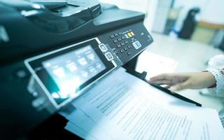 employé de bureau imprime du papier sur une imprimante laser multifonction. copier, imprimer, numériser et télécopier au bureau. technologie d'impression moderne. photocopieuse. document et travail sur papier. scanner. travail de secrétaire. photo