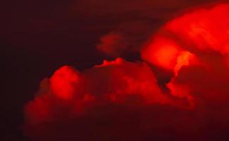 nuages rouges avec un ciel sombre au coucher du soleil. nuages sanglants rouges sur le ciel sombre. ciel crépusculaire du soir. fond de nature pour la saison estivale. ciel rouge dramatique. fond d'enfer ou de paradis. beauté et magie de la nature. photo