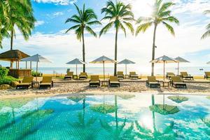 beau parasol et chaise de luxe autour de la piscine extérieure de l'hôtel et du complexe avec cocotier sur ciel bleu