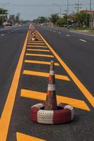 cône en caoutchouc et bande de ligne jaune sur la route. photo