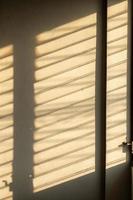 ombre du soleil sur le mur depuis la fenêtre à persiennes. photo