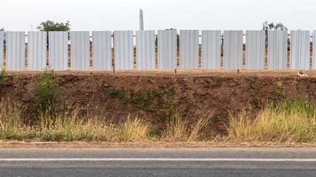 mur de clôture galvanisé au sol près de la route. photo