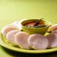 idli avec sambar dans un bol sur fond vert, plat indien nourriture préférée de l'Inde du Sud rava idli ou semoule oisivement ou rava oisivement, servi avec du sambar et du chutney de noix de coco verte. photo