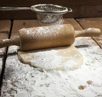 pâte, avec un tas de farine, roulée avec un rouleau à pâtisserie photo