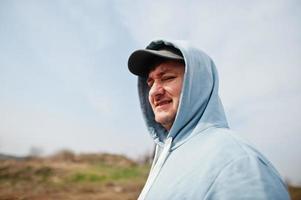portrait en gros plan d'un homme en sweat à capuche bleu et casquette. photo