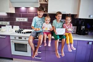 les enfants cuisinent à la cuisine, des moments heureux pour les enfants. quatre enfants, famille nombreuse. photo