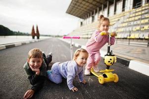 les enfants jouent sur l'asphalte et s'amusent. la famille sportive passe du temps libre à l'extérieur avec des scooters et des patins. photo