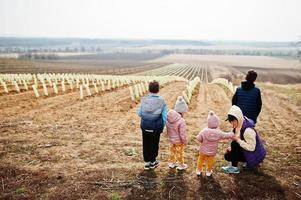 une mère avec des enfants se tient contre le vignoble au début du printemps. photo