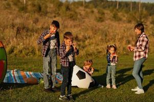 la famille passe du temps ensemble. quatre enfants avec leur mère mangent de la pastèque en plein air. photo