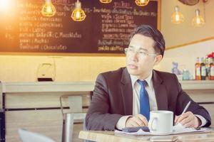 l'homme d'affaires attend avec impatience et pense à un grand projet et travaille dans un café photo