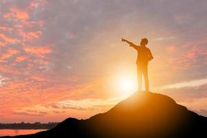 silhouette d'homme d'affaires ingénieur célébration succès bonheur sur fond de ciel de soirée au coucher du soleil au sommet d'une montagne, concept de sport et de vie active, avec un tracé de détourage. photo