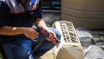 technicien masculin nettoyant le climatiseur à l'intérieur, réparateur lavant le climatiseur des compartiments sales, concepts d'entretien et de réparation photo