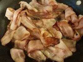 cuisson du bacon dans une poêle ou une poêle sur la cuisinière photo