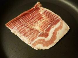 viande de bacon congelée dans une poêle ou une poêle photo