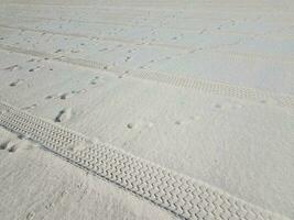 Traces de pneus et empreintes de pas sur la plage peignée photo