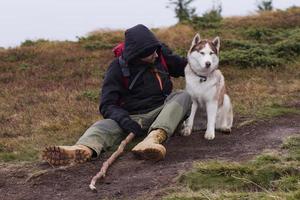 jeune homme avec un chien husky dans les montagnes, voyage avec des chiens photo