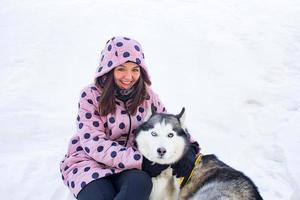 jeune femme avec husky dok assis sur la neige photo