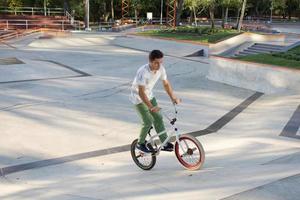 bmx rider formation et faire des tours dans la rue plaza, bicyxle cascadeur dans cocncrete skatepark photo