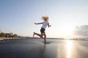 petite fille saute et passe du bon temps sur le trampoline en été photo