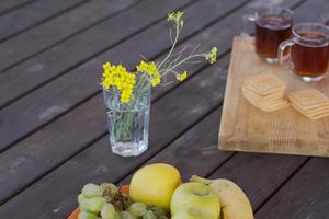 thé, fruits et fleurs sur table en bois photo