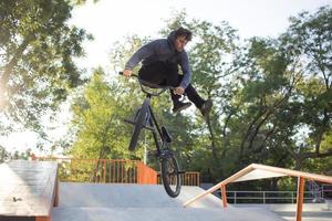 bmx rider formation et faire des tours dans la rue plaza, bicyxle cascadeur dans cocncrete skatepark photo