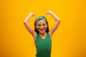 supporter de football, équipe du brésil. Coupe du monde. belle petite fille acclamant son équipe sur fond jaune photo