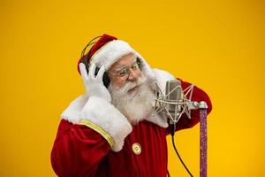 le père noël chante ou parle dans un microphone de studio. joyeux Noël. diffuseur. annonceur. promotion. concept de musique de noël. photo