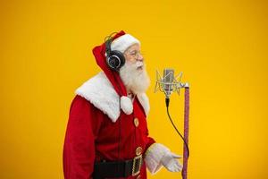 le père noël chante ou parle dans un microphone de studio. joyeux Noël. diffuseur. annonceur. promotion. concept de musique de noël. photo