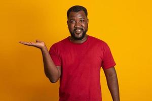 un homme positif à la peau foncée a une expression joyeuse et un large sourire avec des dents blanches, étant de bonne humeur, isolé sur un mur de studio jaune avec espace de copie. mec brésilien d'âge moyen. photo