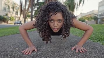 une femme latine faisant des pompes dans le parc. jeune fille faisant des exercices de poussée sur un parc extérieur photo