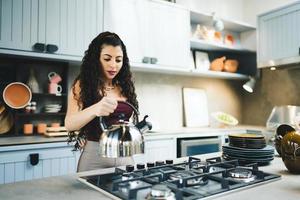 jeune femme latine à la maison préparant du thé dans la cuisine. photo