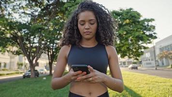 femme latine utilisant un smartphone dans le parc. brésilienne. photo