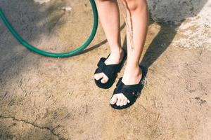 une adolescente asiatique lave une jambe avec un bracelet en caoutchouc d'eau.