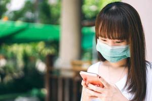 un étudiant adolescent asiatique porte un masque pour le virus corona à l'extérieur le jour. photo