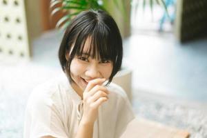 portrait d'une femme asiatique au sourire heureux avec des cheveux courts et un appareil photo à la recherche.