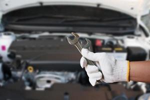 Mécanicien tenant la clé fixant le moteur de voiture photo