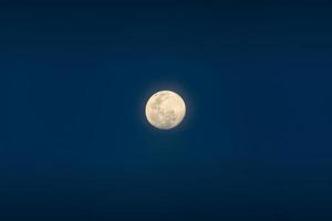 la pleine lune brille sur le ciel bleu au crépuscule photo