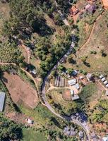 vue aérienne du village rural local avec une route de gravier dans la vallée au loin à la campagne parmi la forêt tropicale photo