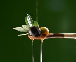 huile tombant sur deux olive avec des feuilles photo