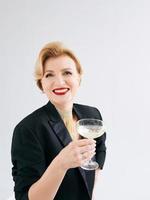 femme élégante et élégante mature en smoking avec un verre de vin mousseux. fête, célébration, concept anti-âge photo