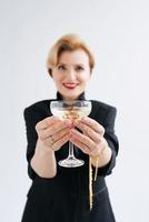 femme élégante et élégante mature en smoking avec un verre de vin mousseux. fête, célébration, concept anti-âge photo