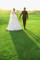 couple de mariage en robe de mariée et costume en regardant le coucher du soleil sur le terrain. amour, famille, concept de tendresse photo
