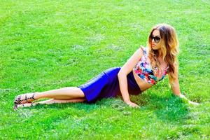 élégante femme slim fit cool dans des lunettes de soleil sur le fond d'herbe. mode, style, tendances, concept de voyage photo